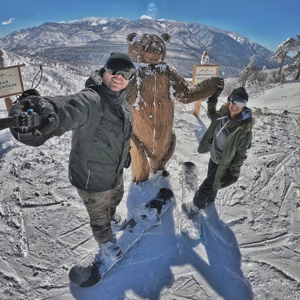 Two people taking a selfie next to a wooden bear